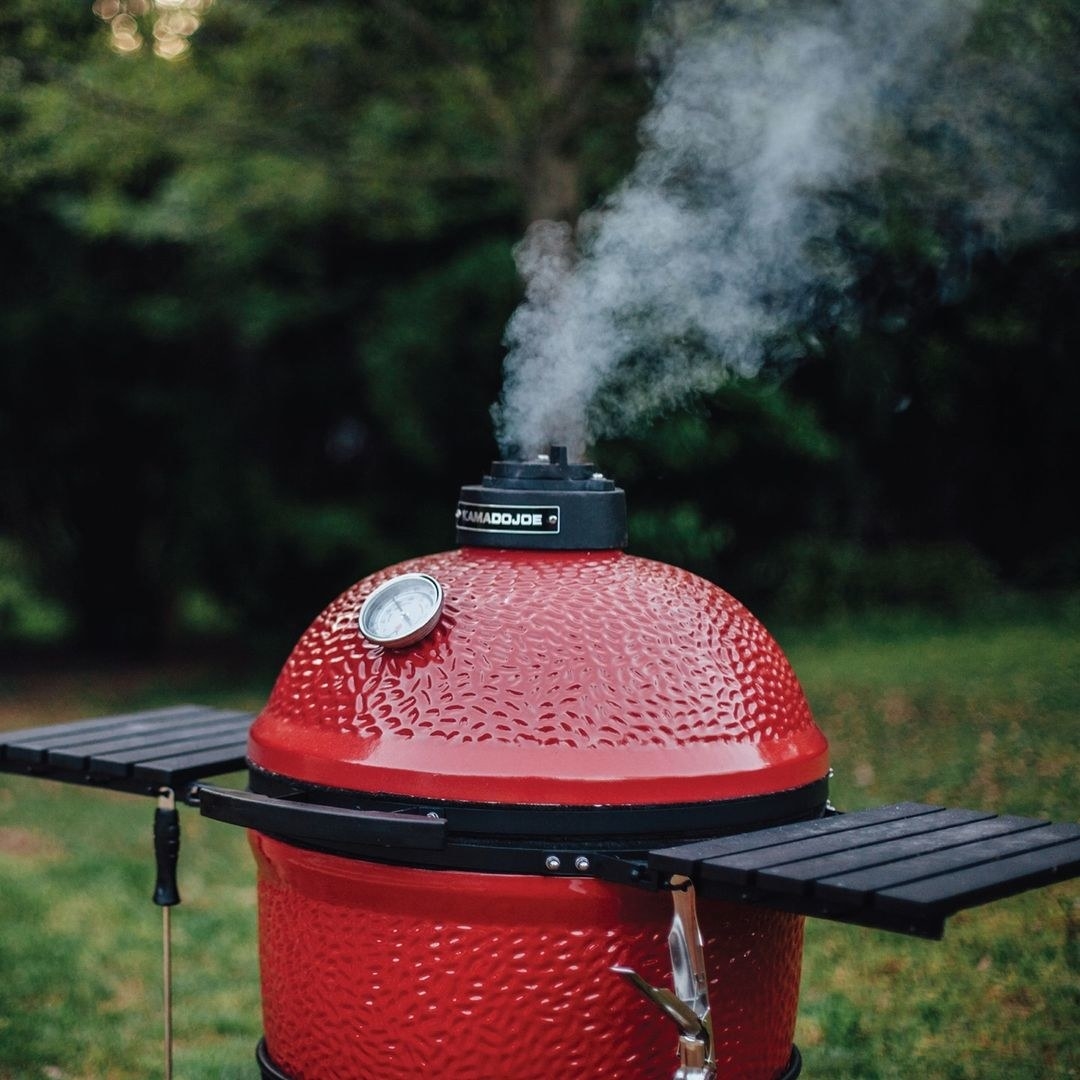 a close up of smoke coming out the top of the kamado joe grill