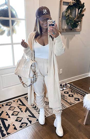 person wearing long cardigan in a beige color over a white top and beige joggers