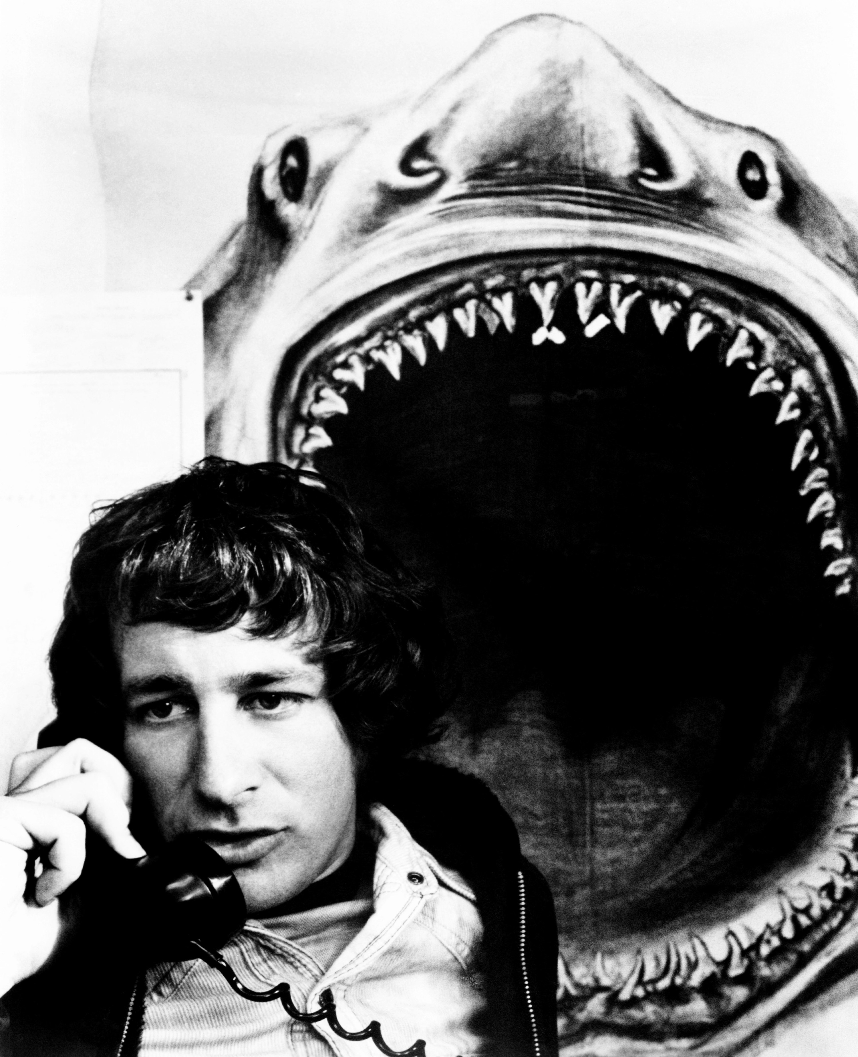 A man takes a phone call in front of a shark