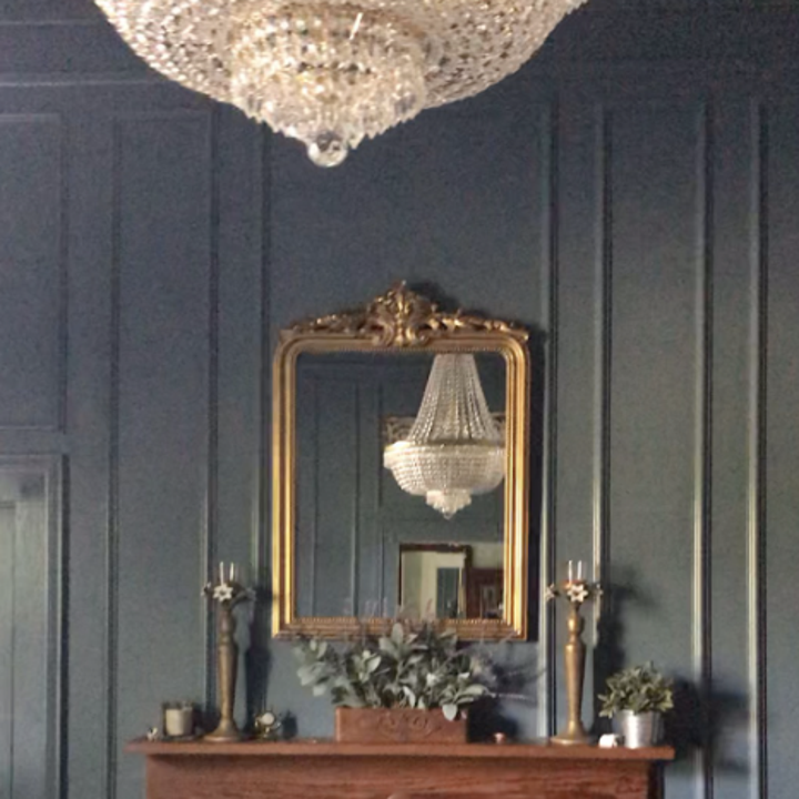 reviewer's mirror hung on a wall opposite a chandelier