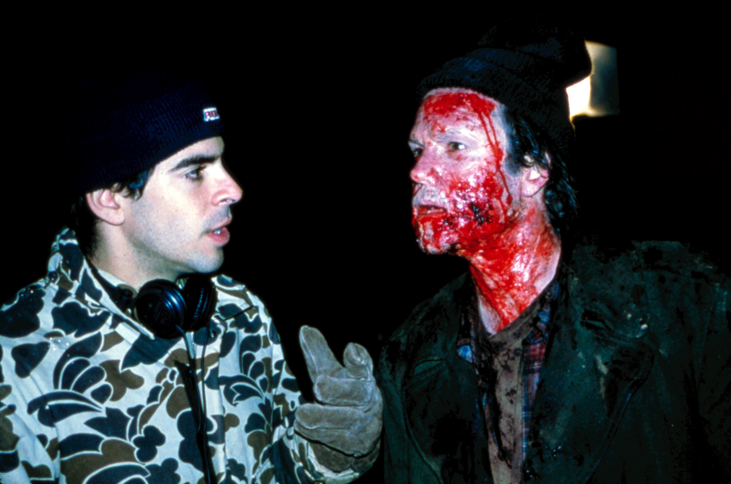 A man speaks to a bloodied actor on set