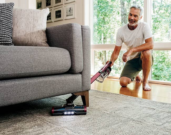 a model using the shark vacuum to clean under a couch