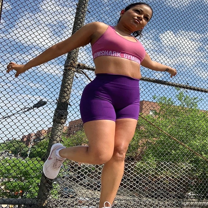reviewer wearing the purple shorts with a pink sports bra