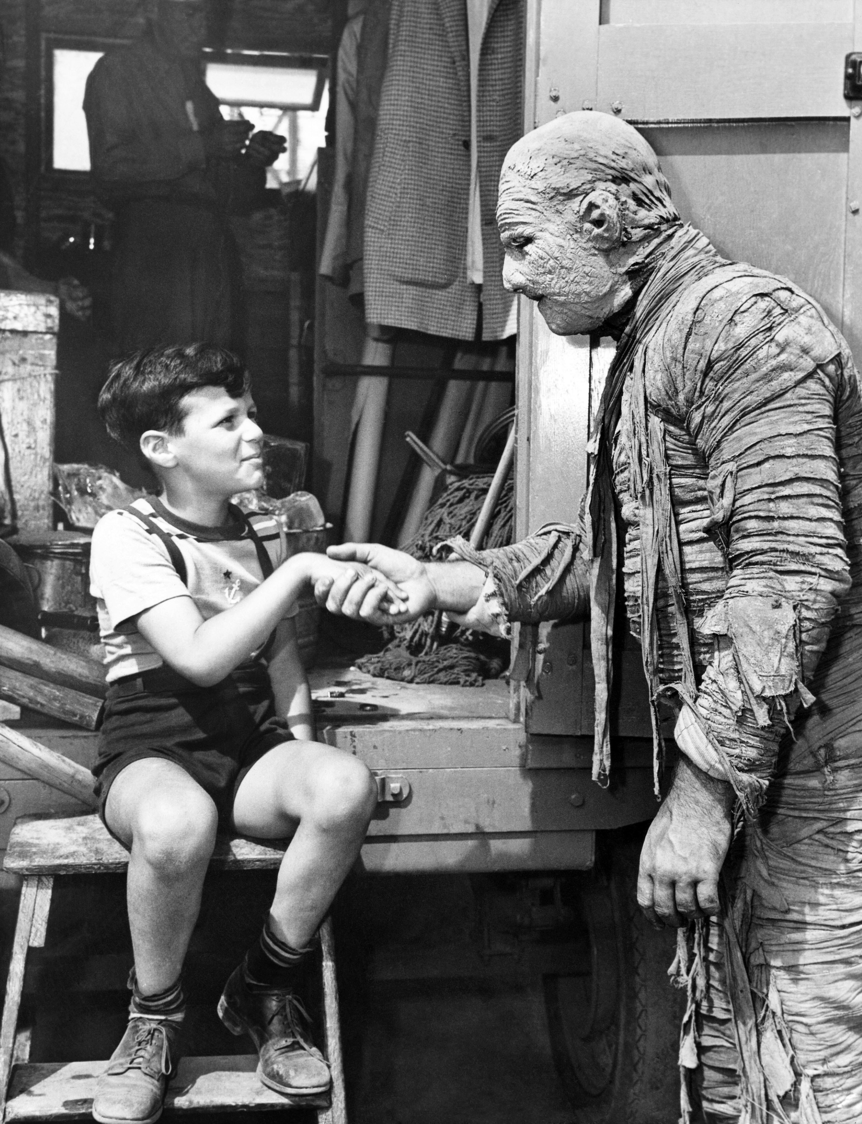 A man in a mummy suit shakes a child&#x27;s hand