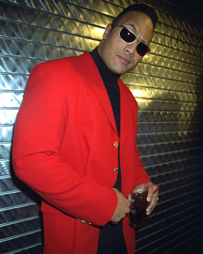 A younger Rock posing for a photo while wearing sunglasses and raising his right eyebrow