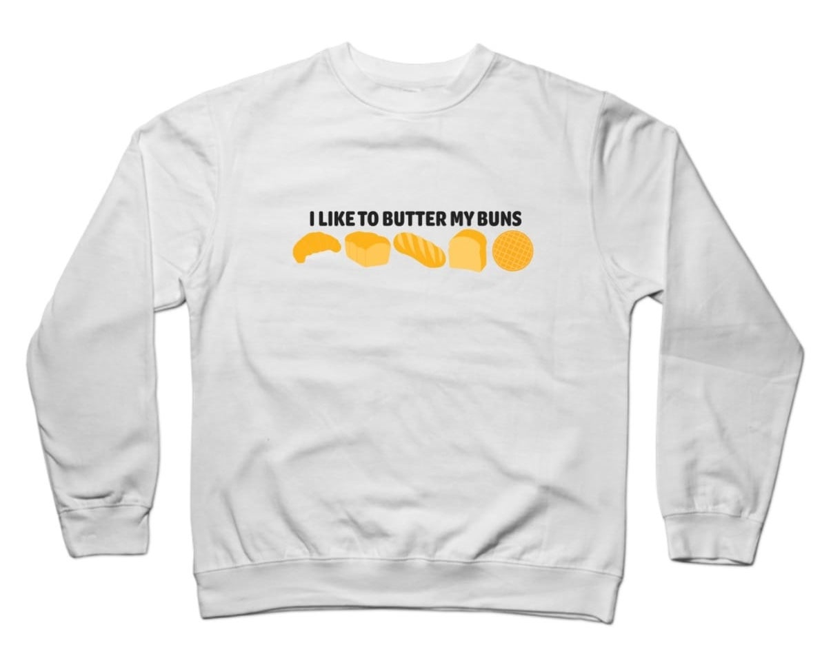A white pull over that has orange, yellow buns with black writing that says &quot;I like to butter my buns&quot;