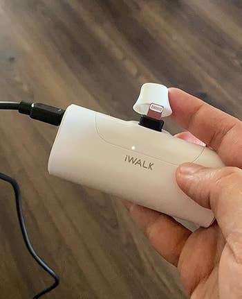 reviewer's hand holding white portable charger