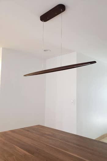 minimalist line light over wooden table in empty room
