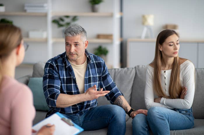 Unhappy mature couple having meeting with marital counselor, discussing relationship problems. Middle-aged spouses sitting on couch at therapist&#x27;s office in need of professional help