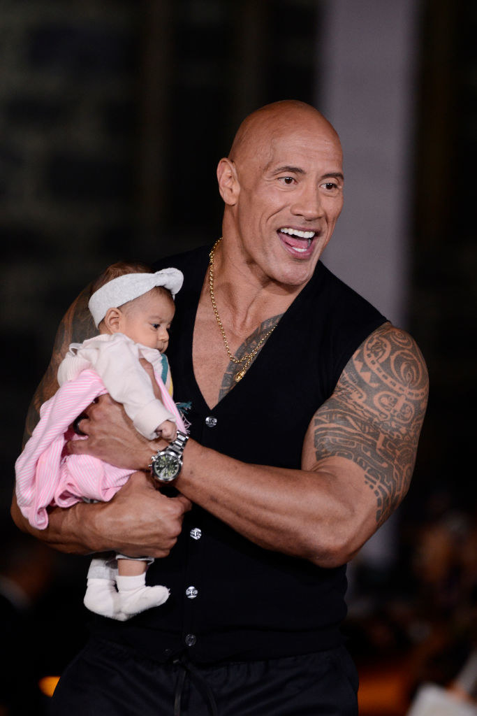 The Rock holding the baby who has no idea what is going on