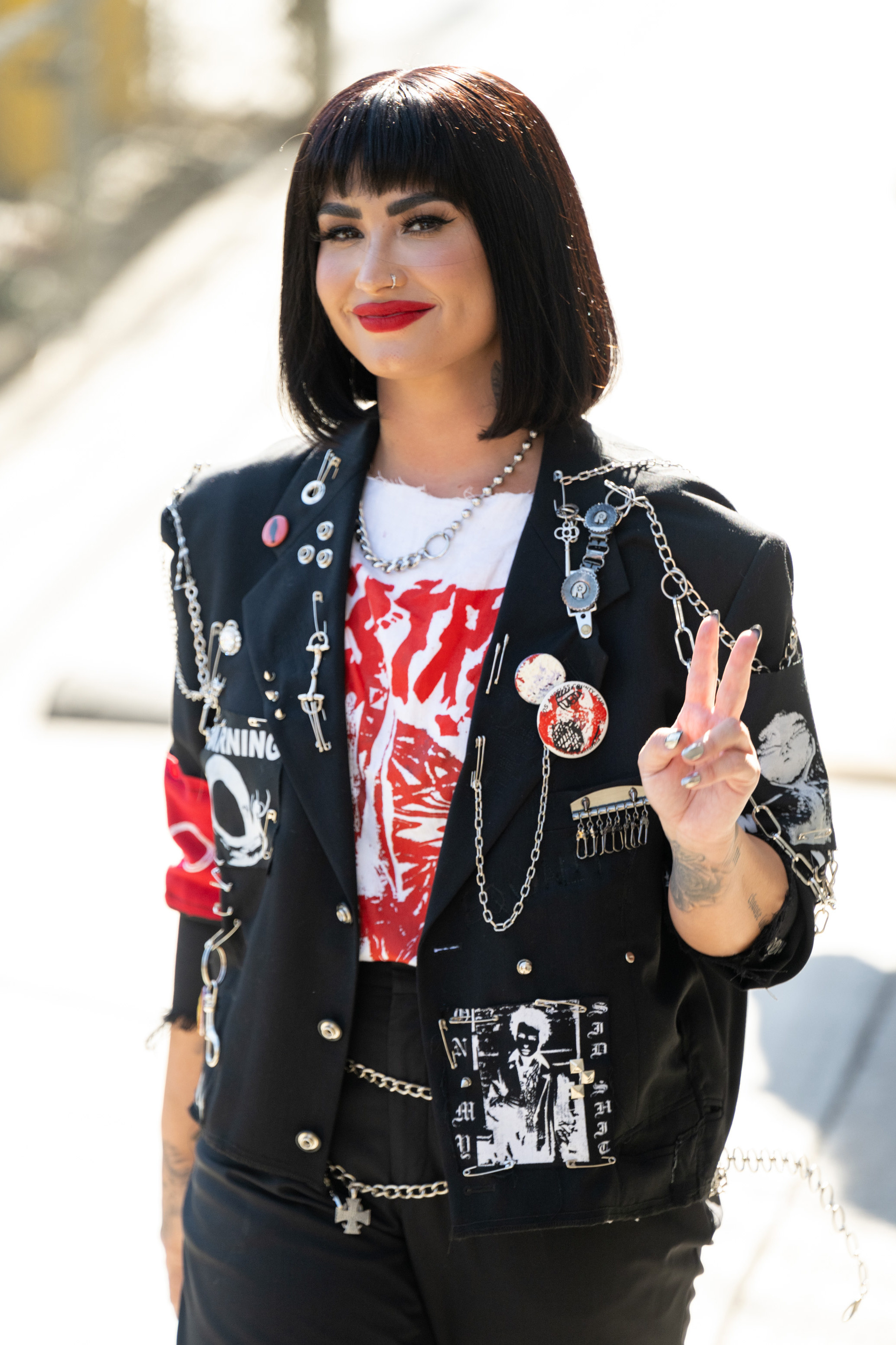Demi throwing a peace sign while walking outside