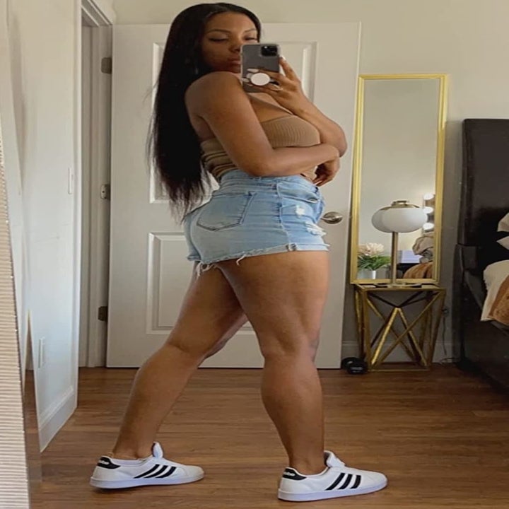 reviewer wearing the white and black sneakers with denim shorts and a tube top