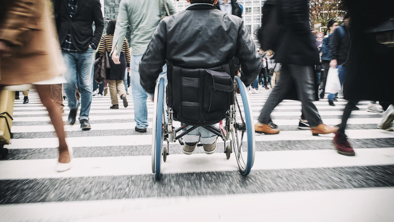 person crossing a crowded sidewalk in a wheelchair