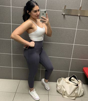 reviewer wearing leggings in grey at the gym with converse sneakers