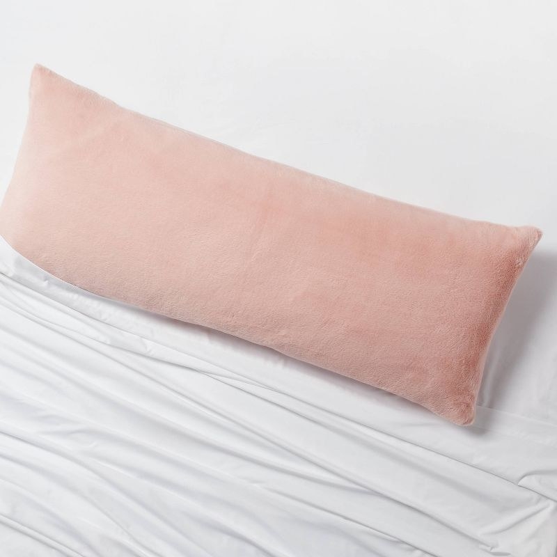 the soft pink cover on a pillow on a bed with white sheets