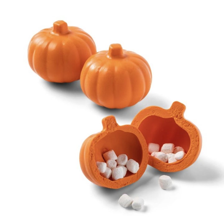 The three mini pumpkin cocoa bombs, one split in half to show mini marshmallows