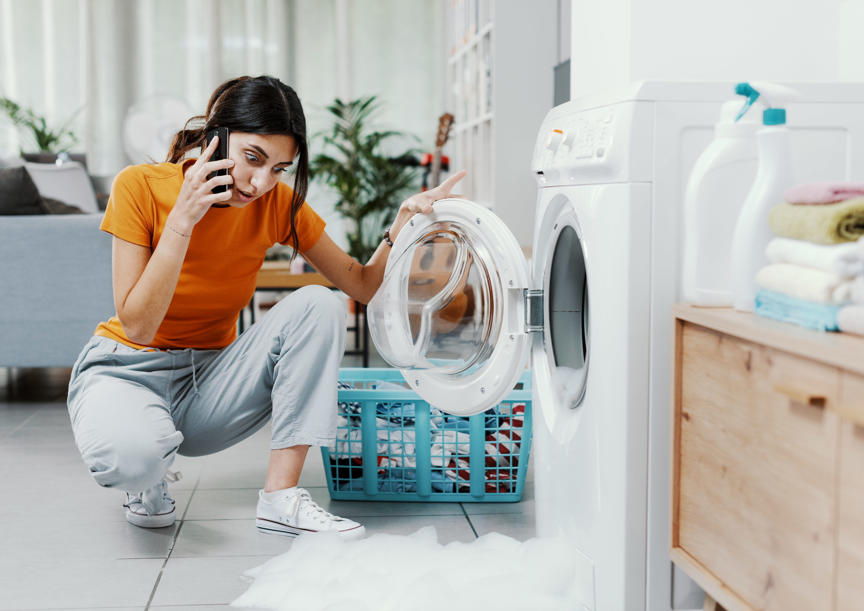 woman calling for help with her broken washing machine