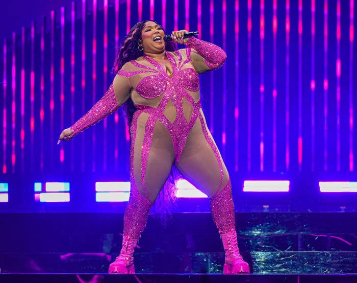 Lizzo singing onstage in a glittery bodysuit with cutouts