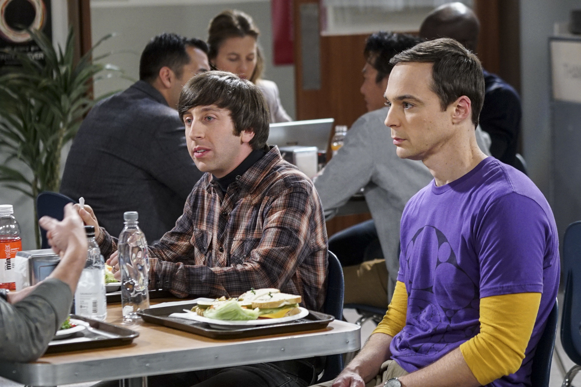 Simon and Jim sitting next to each other in a cafeteria during a scene