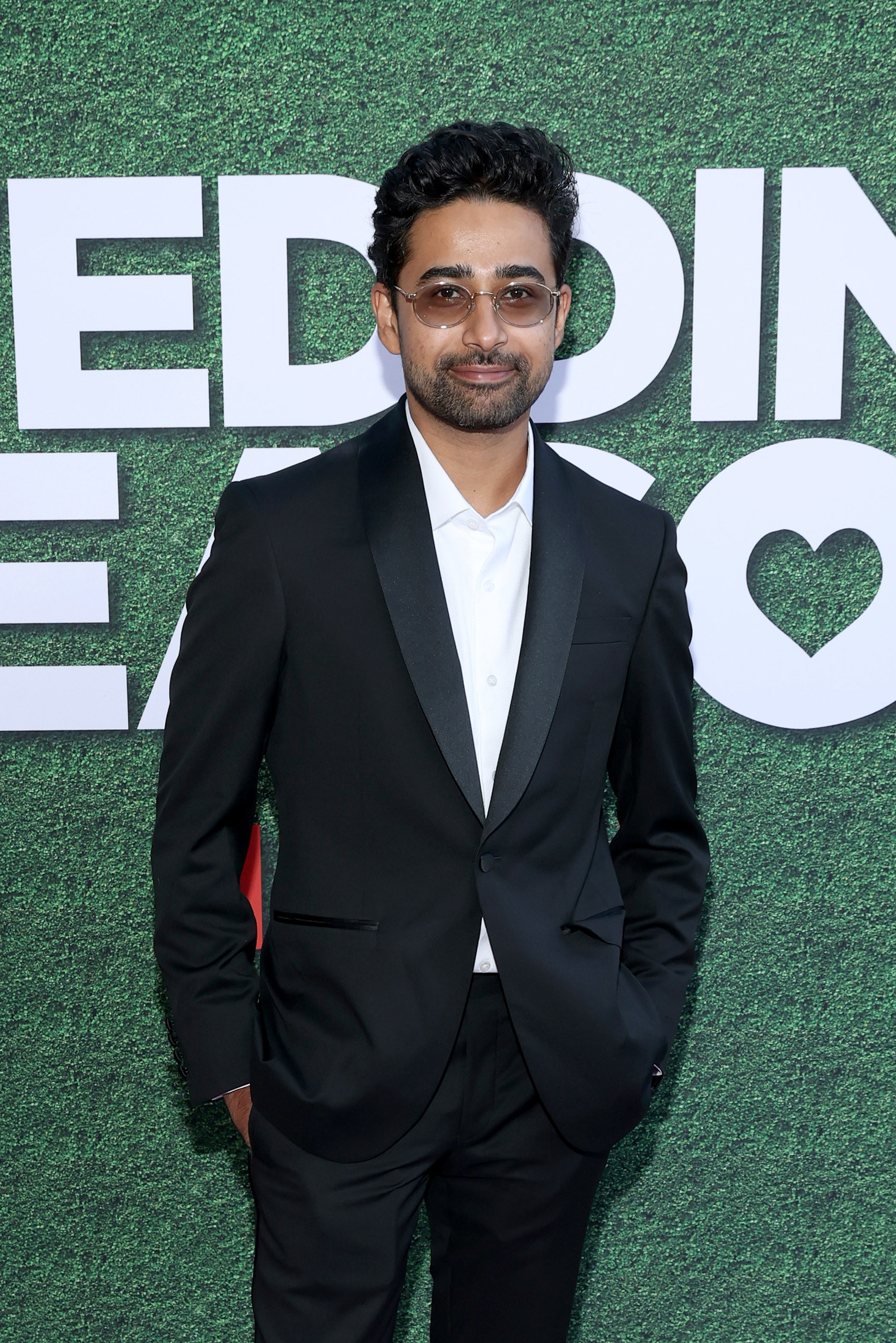 Suraj smiling in a suit wearing shades at an event