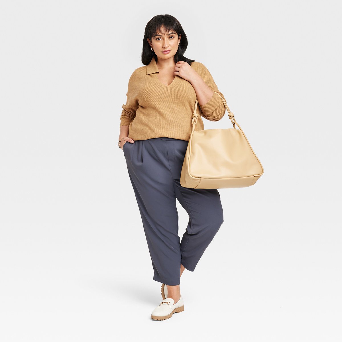 Woman wears collared top with tapered pants, trendy shoes and tote