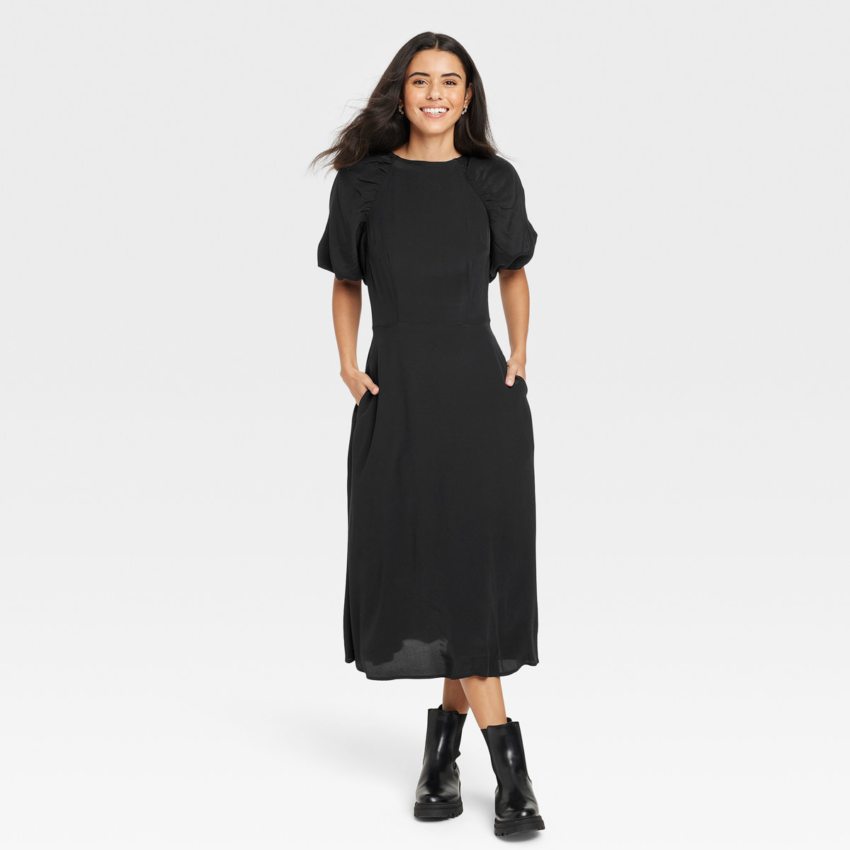 Smiling woman wears midi dress with hands in pockets