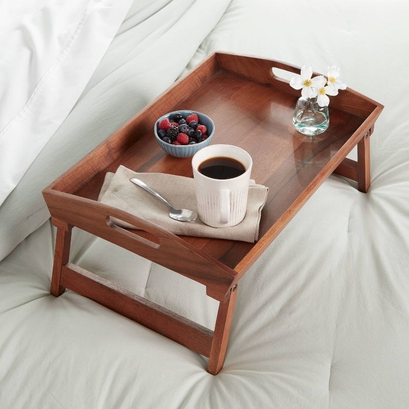 the wooden tray with breakfast on a made bed
