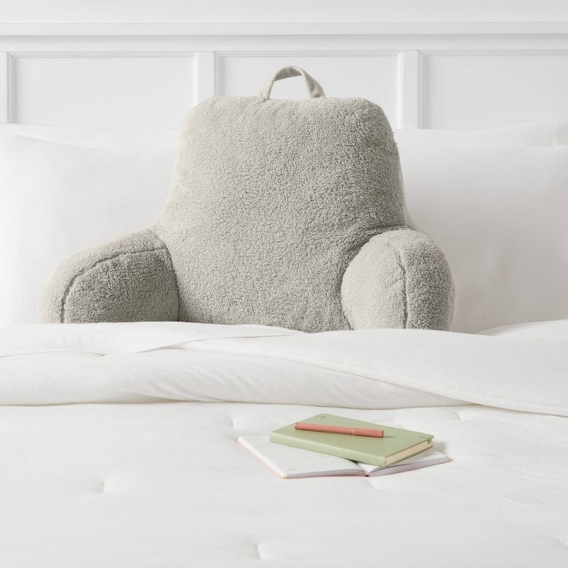 the grey sherpa pillow in a white decorated bed
