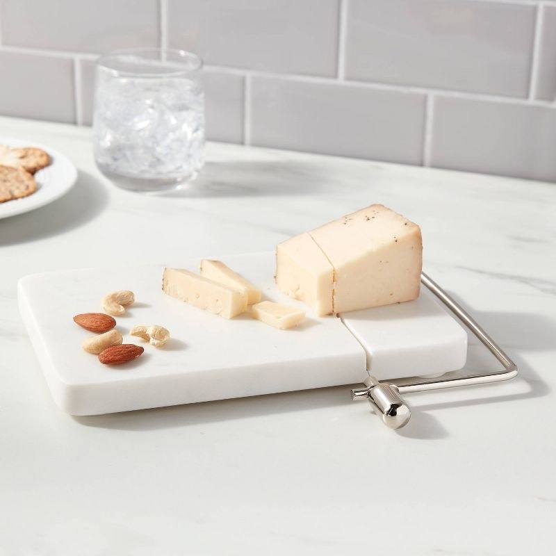the white marble cheese slicer with cheese and nuts on it