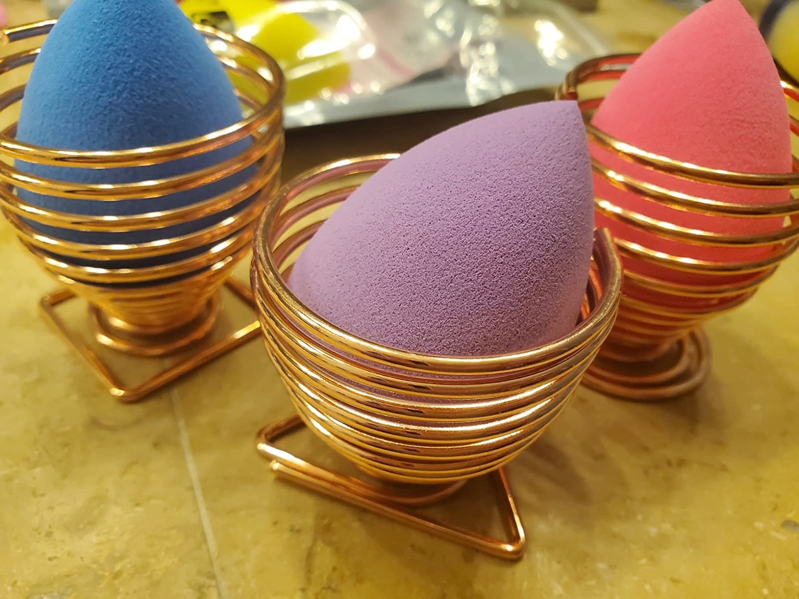 three multi-colored makeup sponges in display cups