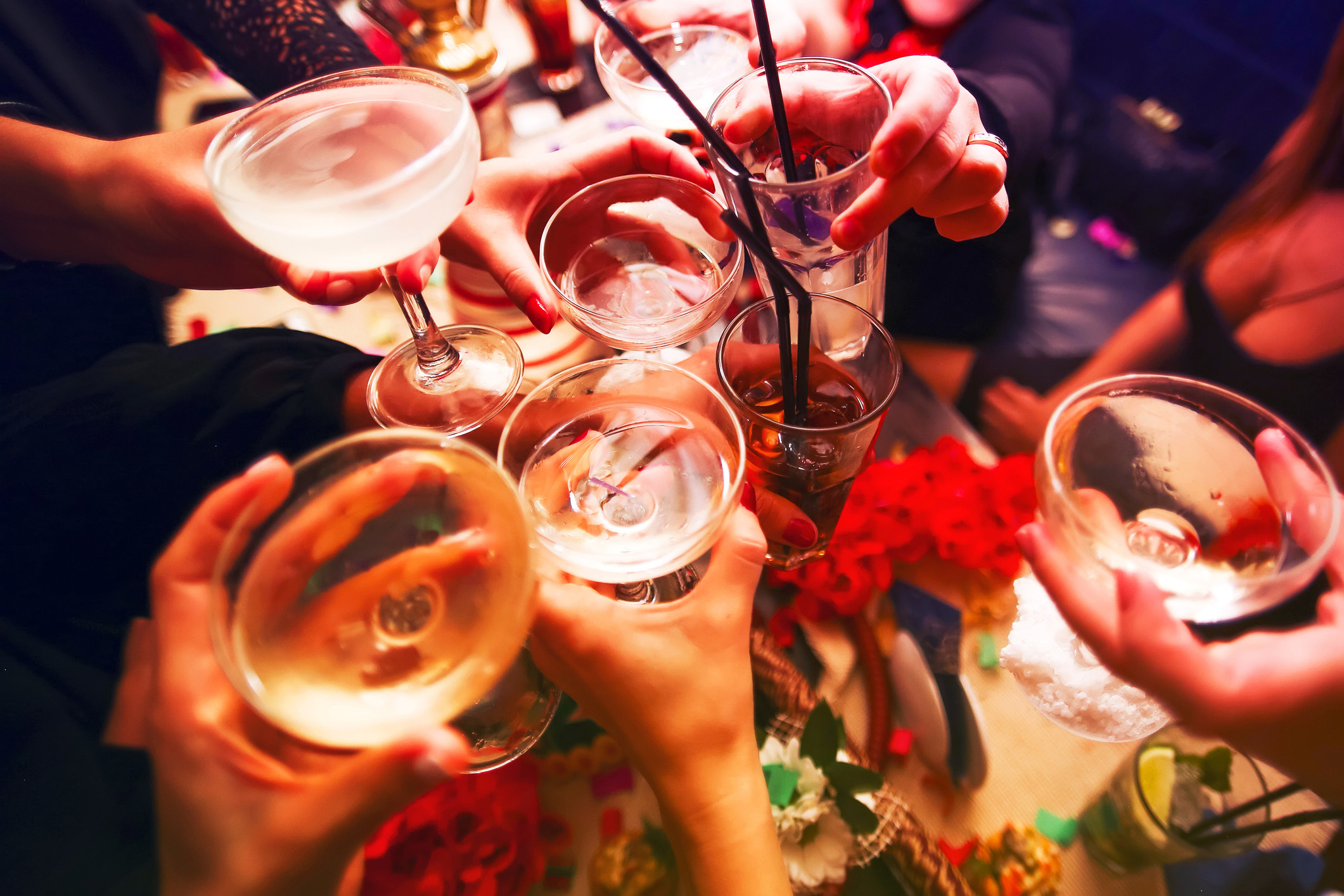 A stock image of people holding glasses of presumed alcohol up to cheers