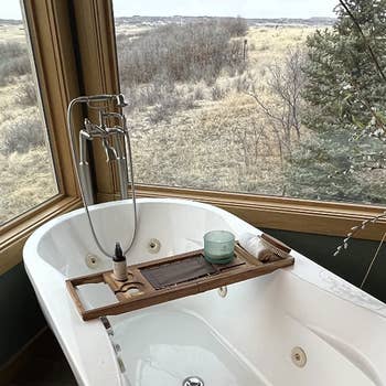 reviewer's bathtub with windows on either side and the caddy displayed on top