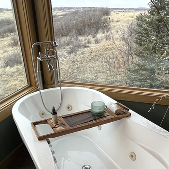 reviewer's bathtub with windows on either side and the caddy displayed on top