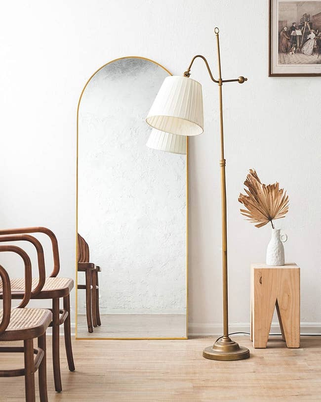 arched mirror in room with chairs and a lamp