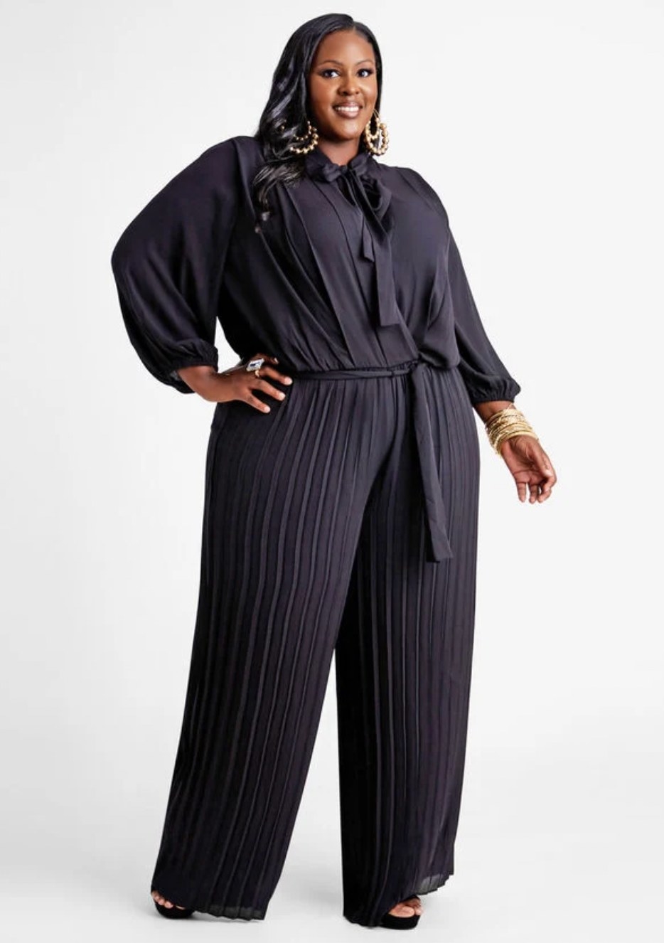 Model in the dark blue jumpsuit featuring bow tie neck collar and tie at waist