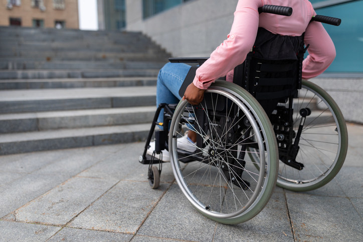 person in a wheelchair facing a set of stairs