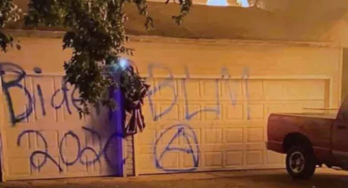A garage is spray-painted with the messages &quot;Biden 2020,&quot; &quot;BLM,&quot; and an anarchy symbol