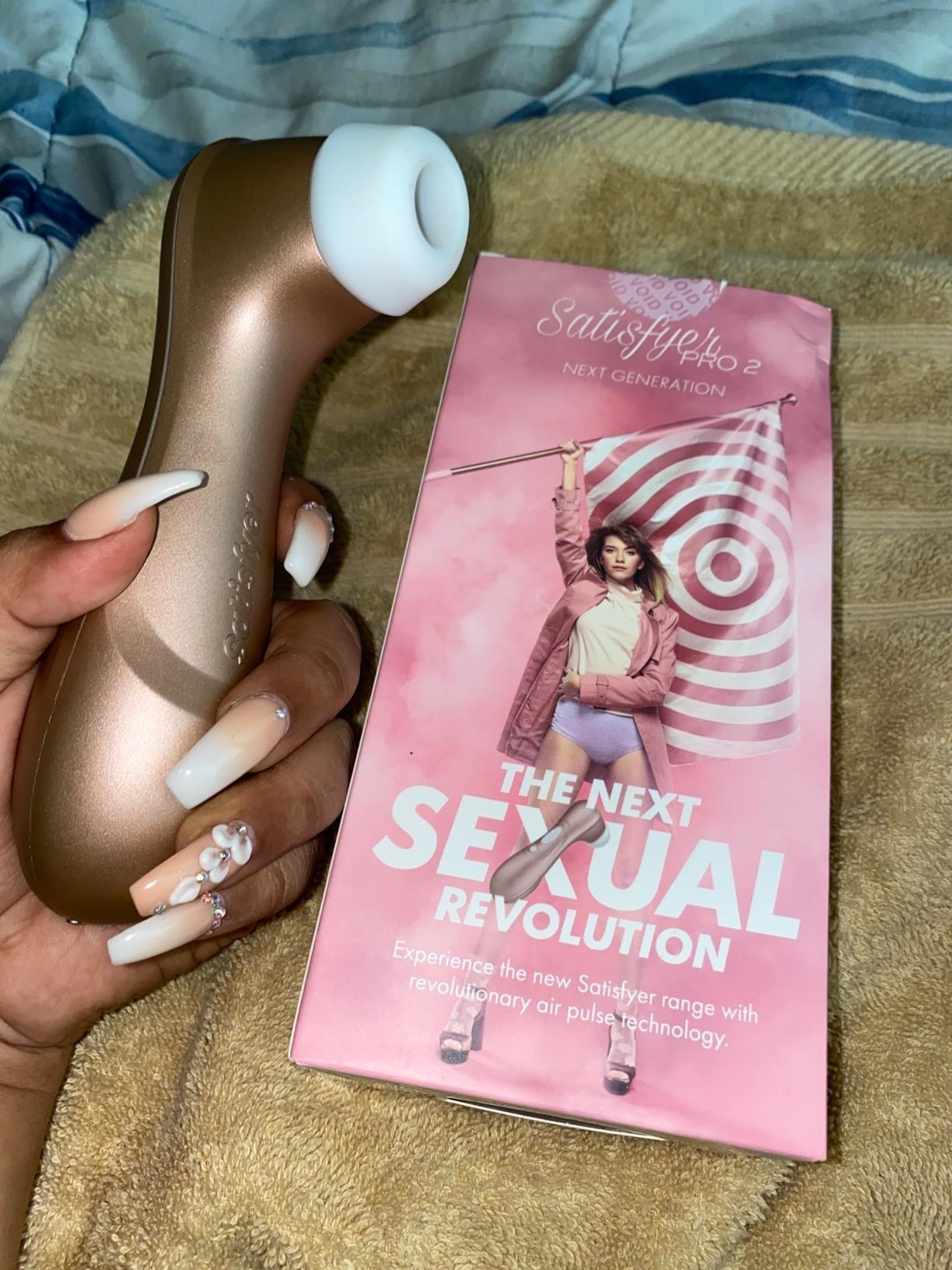 Reviewer holding rose gold vibrator next to pink box