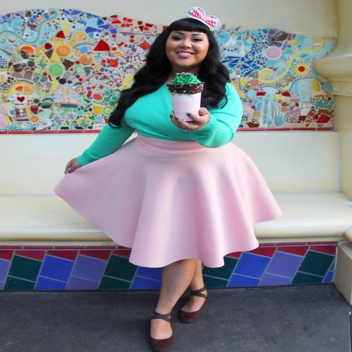 reviewer wearing the sweater in teal with a pink skater skirt