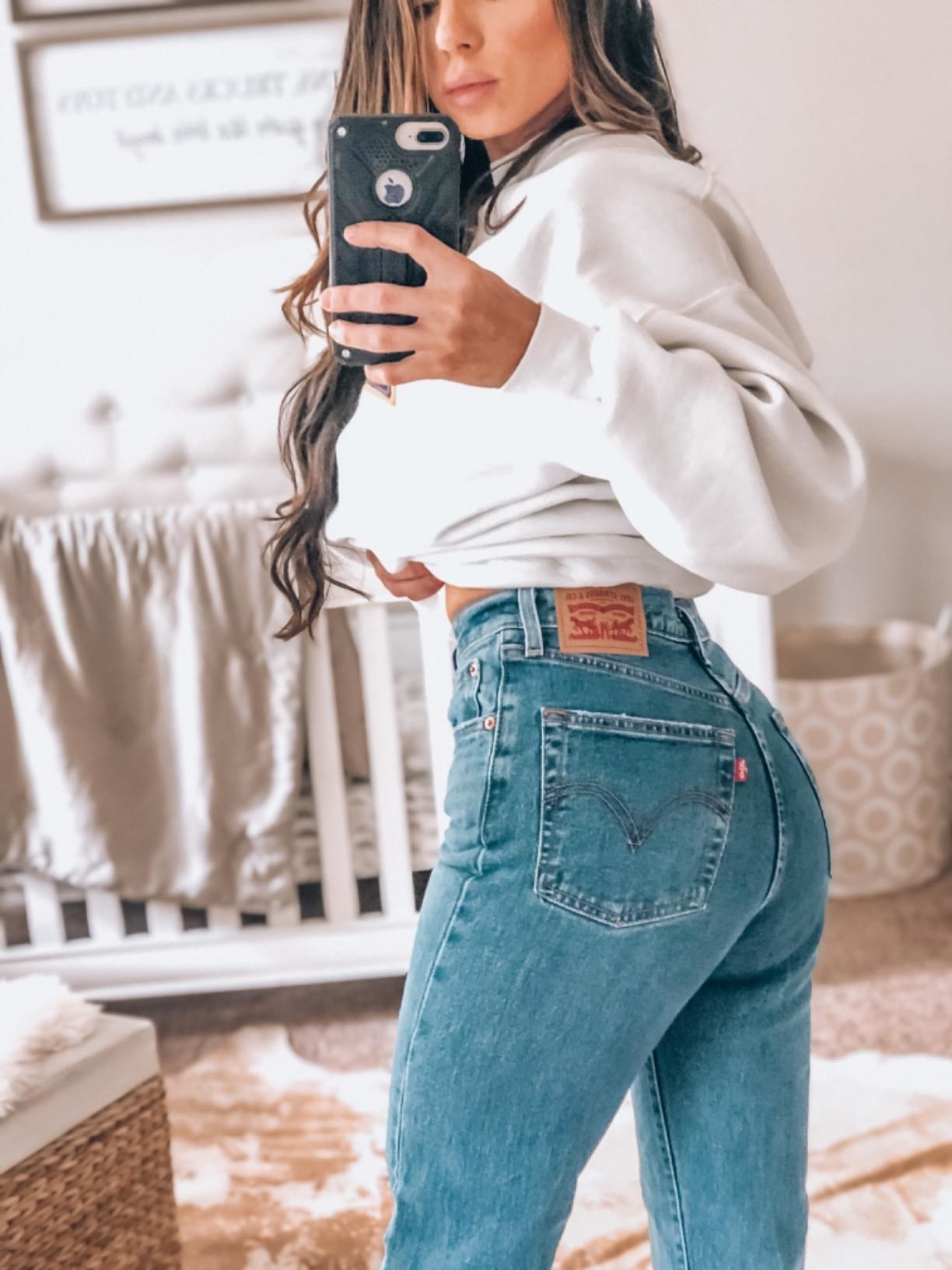 A reviewer showing the back of the jeans