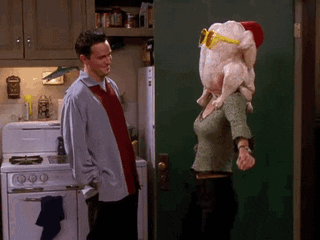 Monica Geller dances with a turkey on her head as Chandler Bing laughs