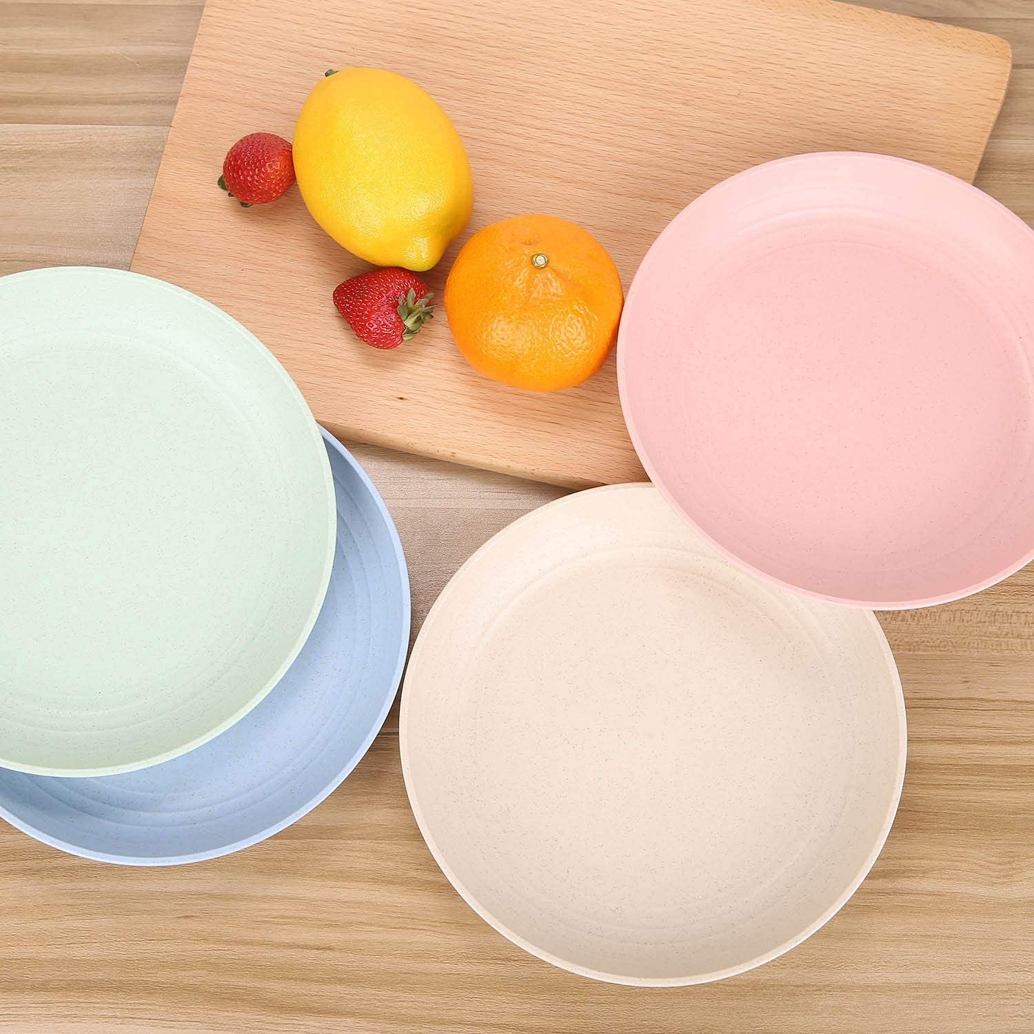 four plates on a table, one green, one blue, one pink, and one pale peach