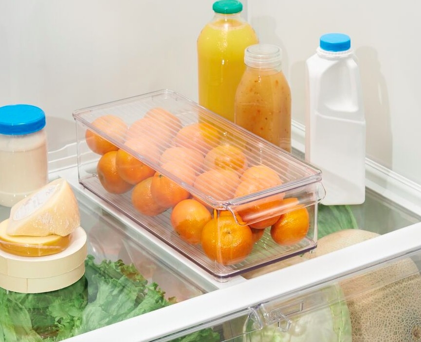the clear bin in a refrigerator with oranges inside
