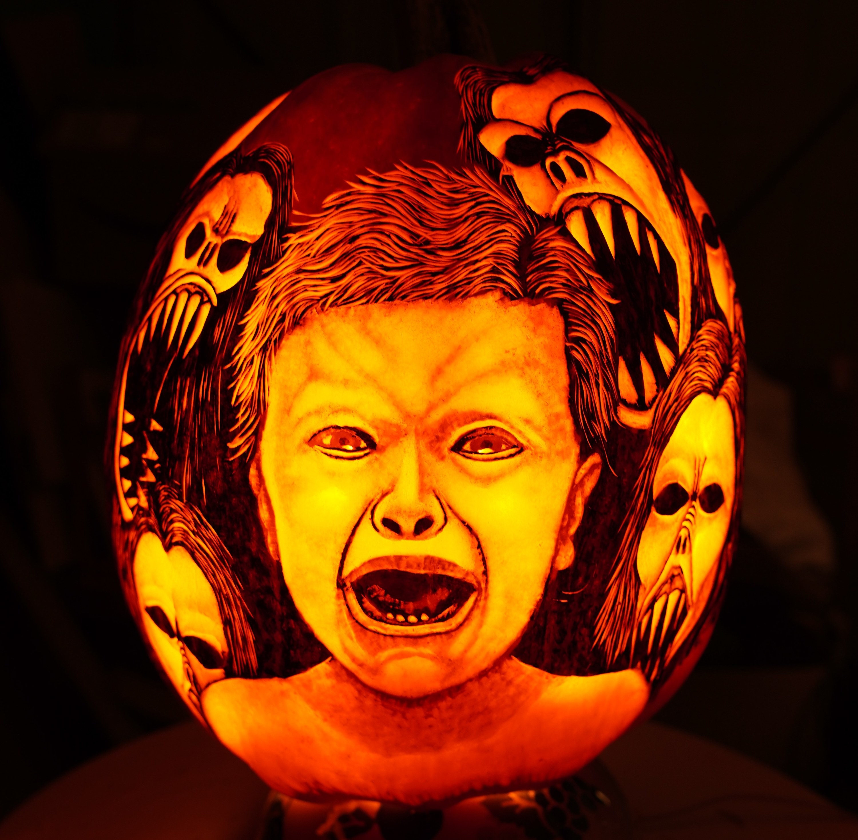 a child surrounded by monsters carved on a pumpkin