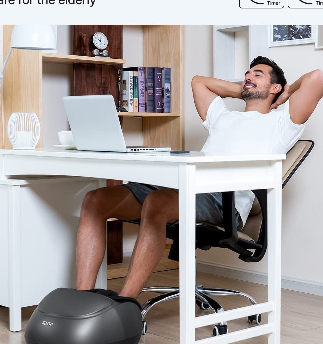 A person sitting at a desk with their feet in the massager
