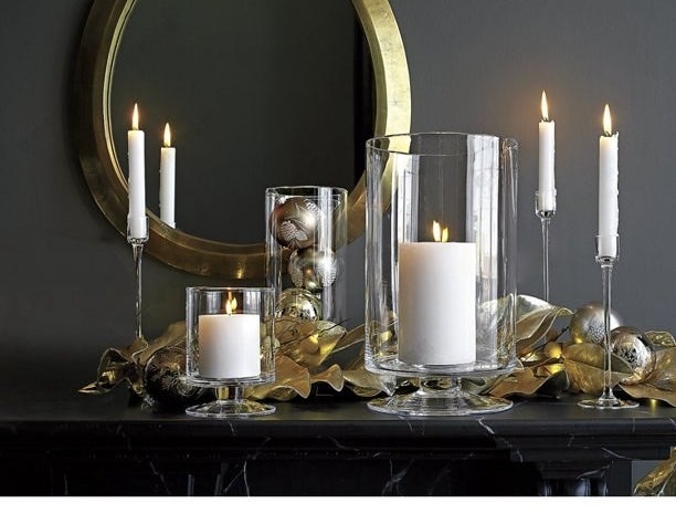 Candle holders on black mantel with a gold mirror hung above it