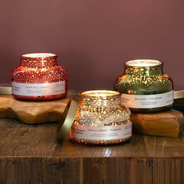 Three lit candle jars on a wood table