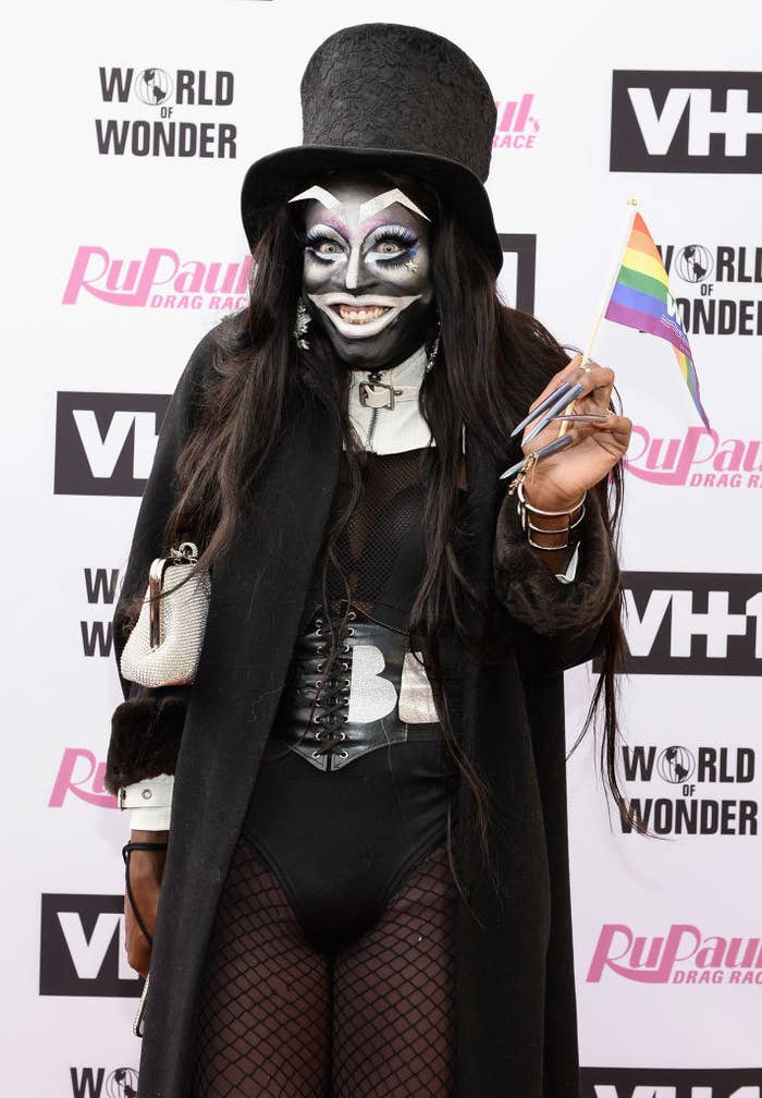 Someone dressed as the Babadook and waving a mini Pride flag at a red carpet event