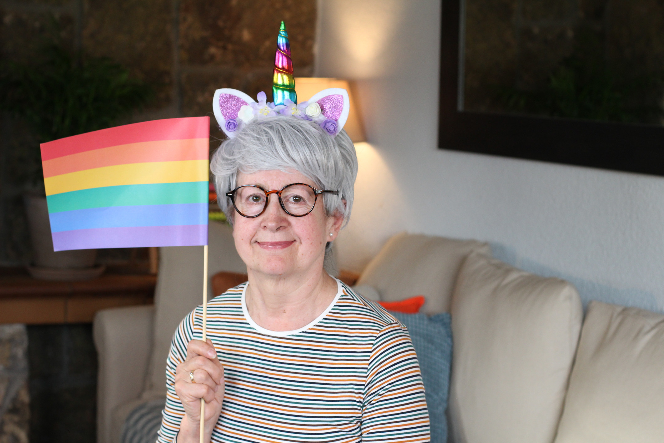 A person wearing a unicorn headband and holding a Pride flag