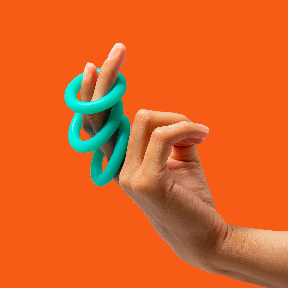 Model holding three turquoise cock rings of different sizes